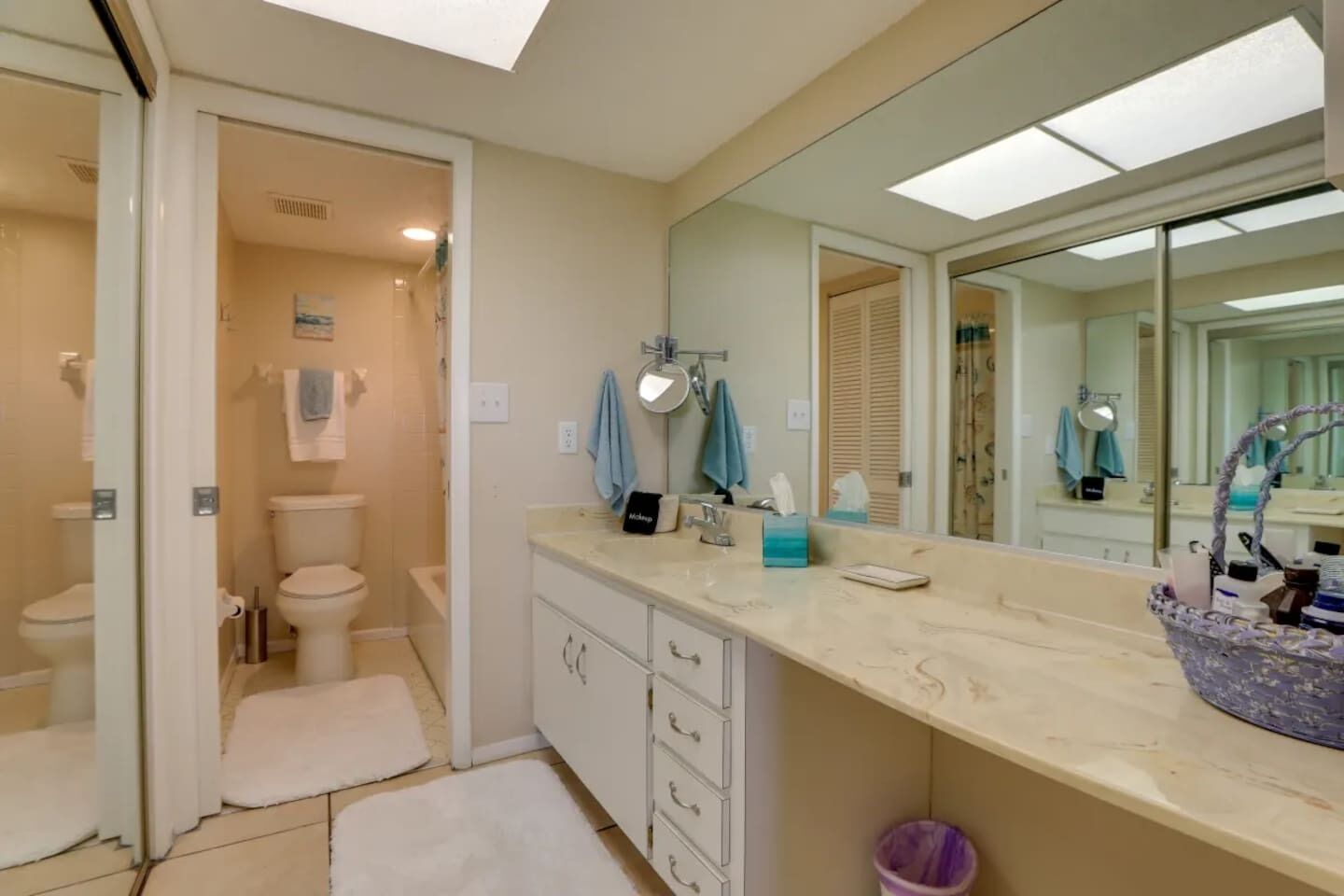 Un baño moderno con un espejo grande, inodoro, lavabo y zona de ducha.