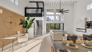 Ein modernes Interieur mit einer Wand aus Holzlamellen, einer Treppe, einer Sitzecke mit Kamin und einem Essbereich.