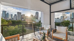 Ein Balkon mit Blick auf die Stadt, Korbmöbel und einem Blumentopf.