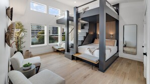 Ein modernes Schlafzimmer mit Etagenbett, Schreibtisch und großem Fenster mit Blick auf die Stadt.