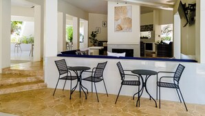 A modern interior with a bar area, stone flooring, and a ceiling fan.