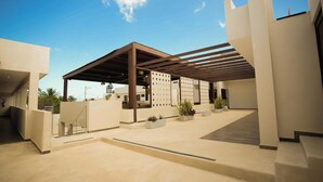 A modern building with a covered outdoor area, a staircase, and potted plants. - Hotel Yuhome Telchac (Telchac Puerto)