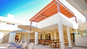 A rooftop lounge area with sun loungers and umbrellas, wooden tables, and a view of the sky. - Hotel Yuhome Telchac (Telchac Puerto)