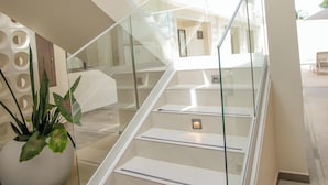 A modern interior with a glass railing staircase, a potted plant, and a clean, white color scheme. - Hotel Yuhome Telchac (Telchac Puerto)