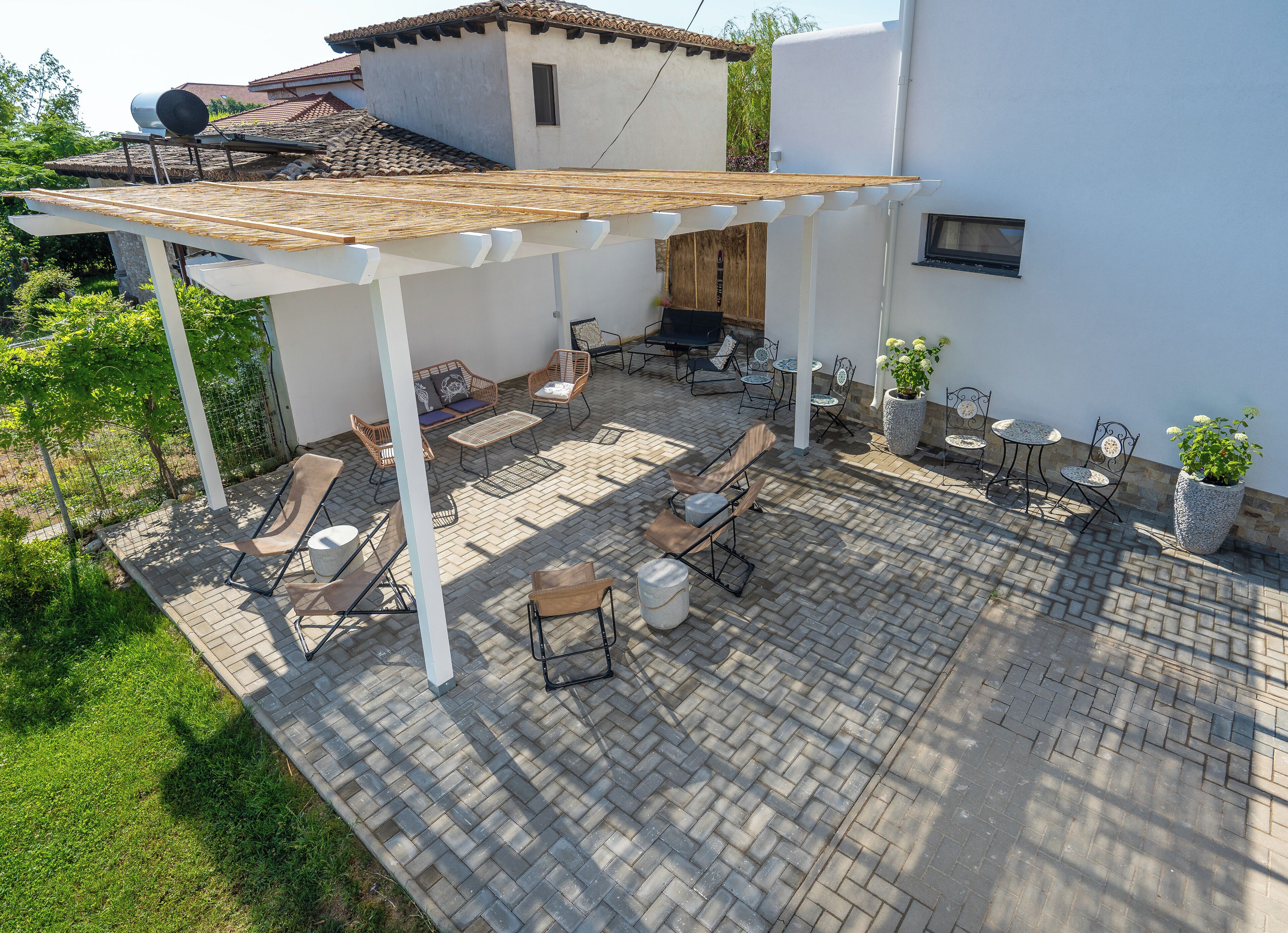 A patio with outdoor furniture, a pergola, and a potted plant.