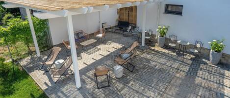 A patio with outdoor furniture, a pergola, and a potted plant.