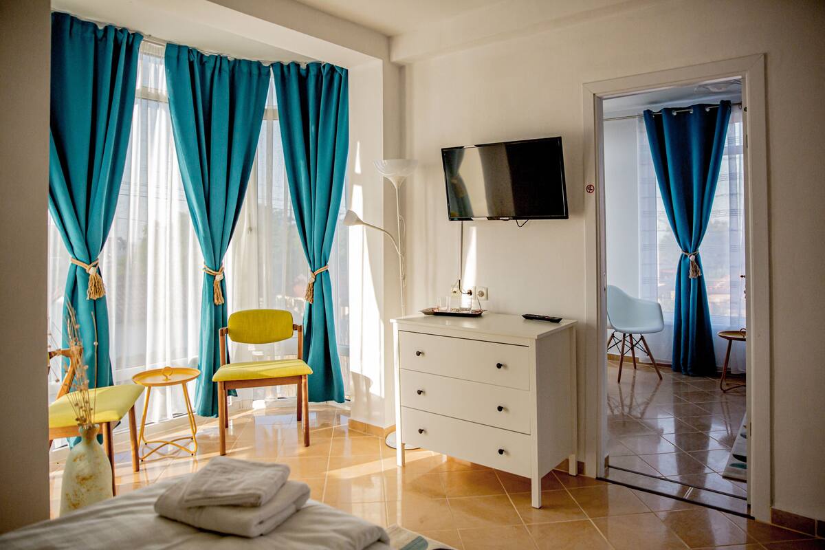 A hotel room with a bed, a desk, a chair, a TV, and a wardrobe.