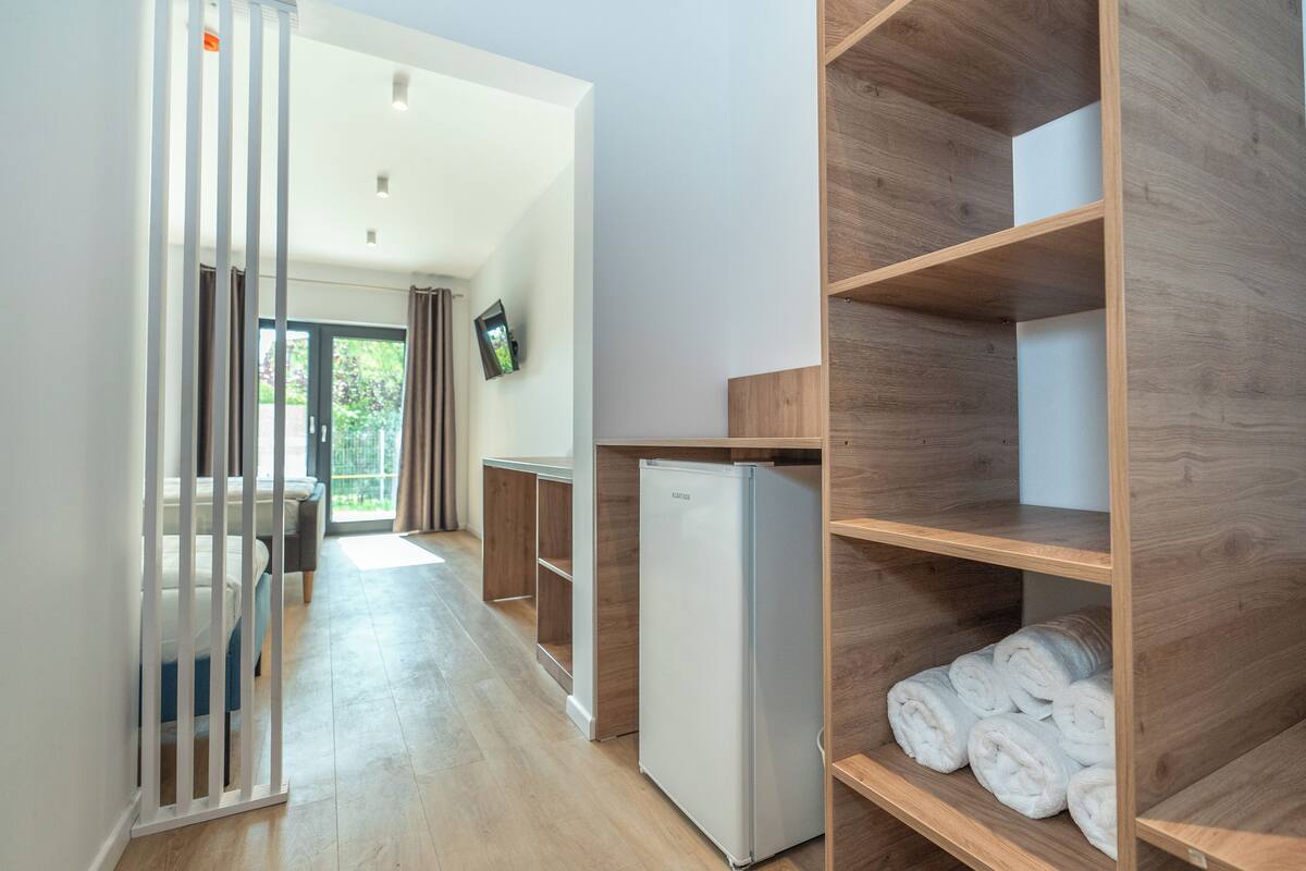 A modern kitchen with a built-in refrigerator, wooden shelving, and a view of the outdoors.