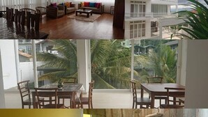 A multi-room hotel with a dining area, a balcony with a view of palm trees, a bedroom with a bed and nightstand, and a bathroom with a shower and toilet. - Green Royal Villa (Kandy)