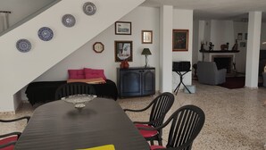 A dining area with a dark wooden table, red and black chairs, a pink sofa, and a staircase leading to another level. - La Gaspara's loft (Estepona)