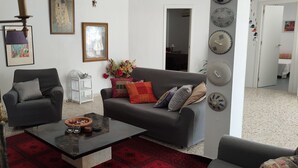 A living room with a sofa, armchair, coffee table, and decorative items. - La Gaspara's loft (Estepona)