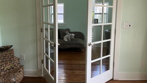 Una habitación con suelo de madera, un sofá estampado de leopardo y una puerta blanca con paneles de vidrio.