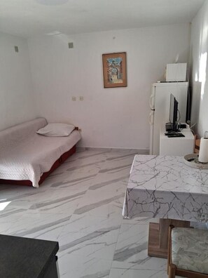 Una habitación con una cama, un escritorio con computadora, una silla y un cuadro en la pared.