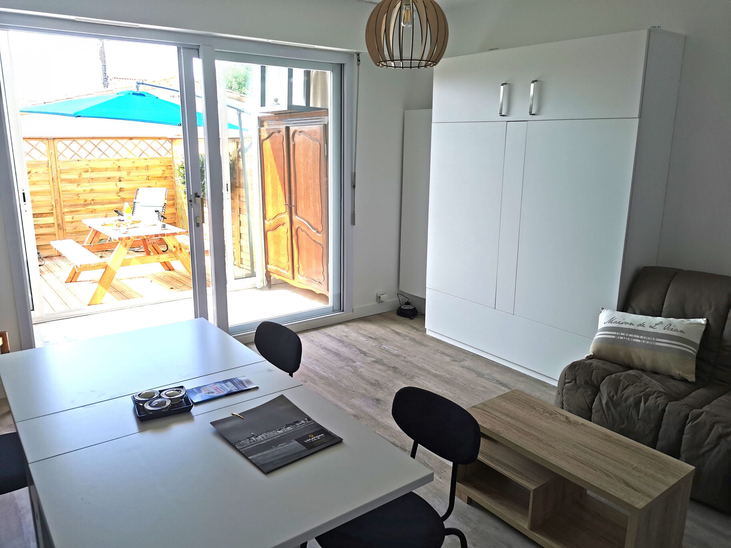 Una habitación con una mesa de comedor, sillas, un sofá, un armario y un ventanal corredero que da a un patio exterior.