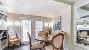 A dining area with a round table, four chairs, and a large mirror on the wall.