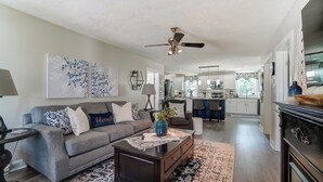 A spacious living room with a gray sofa, a coffee table, and a ceiling fan.
