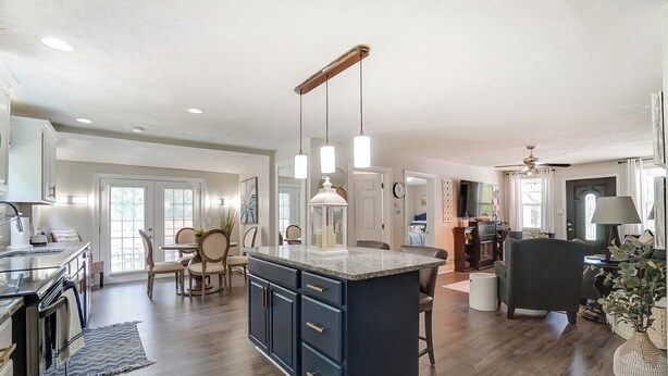 A spacious kitchen with a central island, wooden flooring, and pendant lighting.