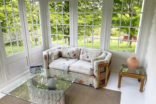 Relax in this serene room with a large sectional sofa, glass coffee table, and stunning garden view.