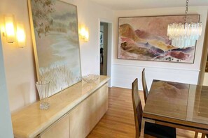 Enjoy meals in this stylish dining area with a polished table, comfortable chairs, and a beautiful abstract painting.