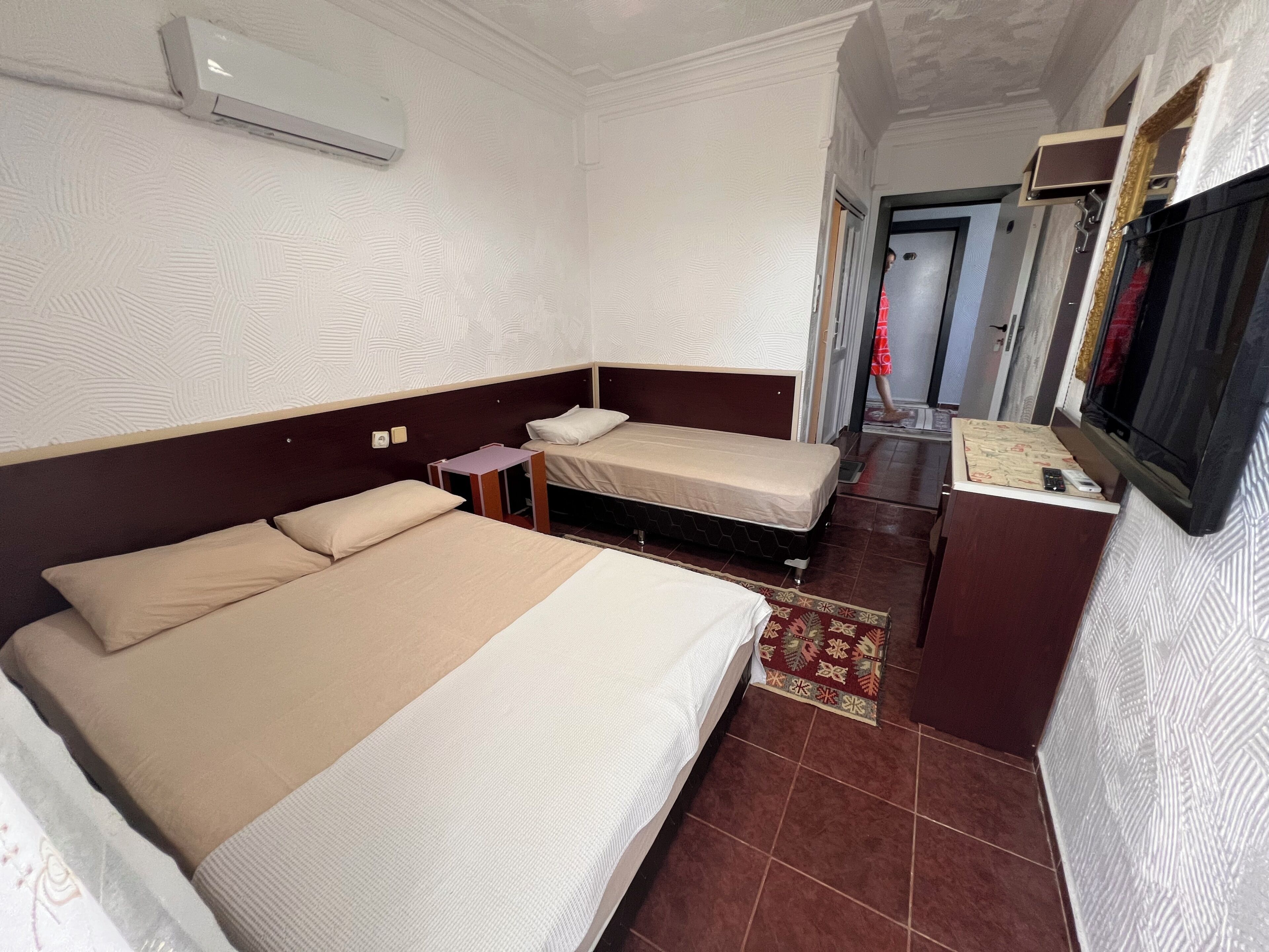 A hotel room with two beds, a TV, and a small desk.