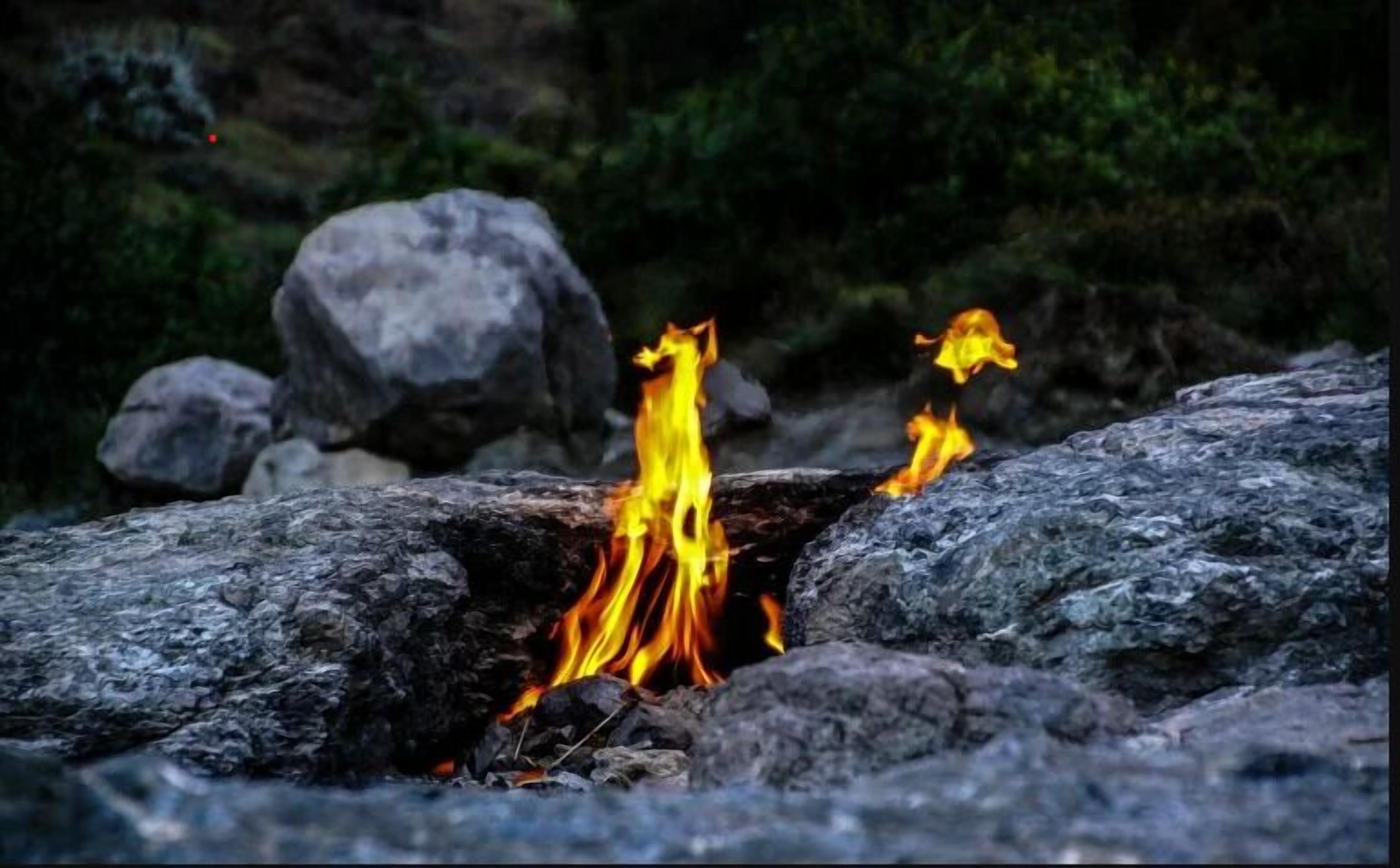 A campfire burning in a rocky outdoor setting.