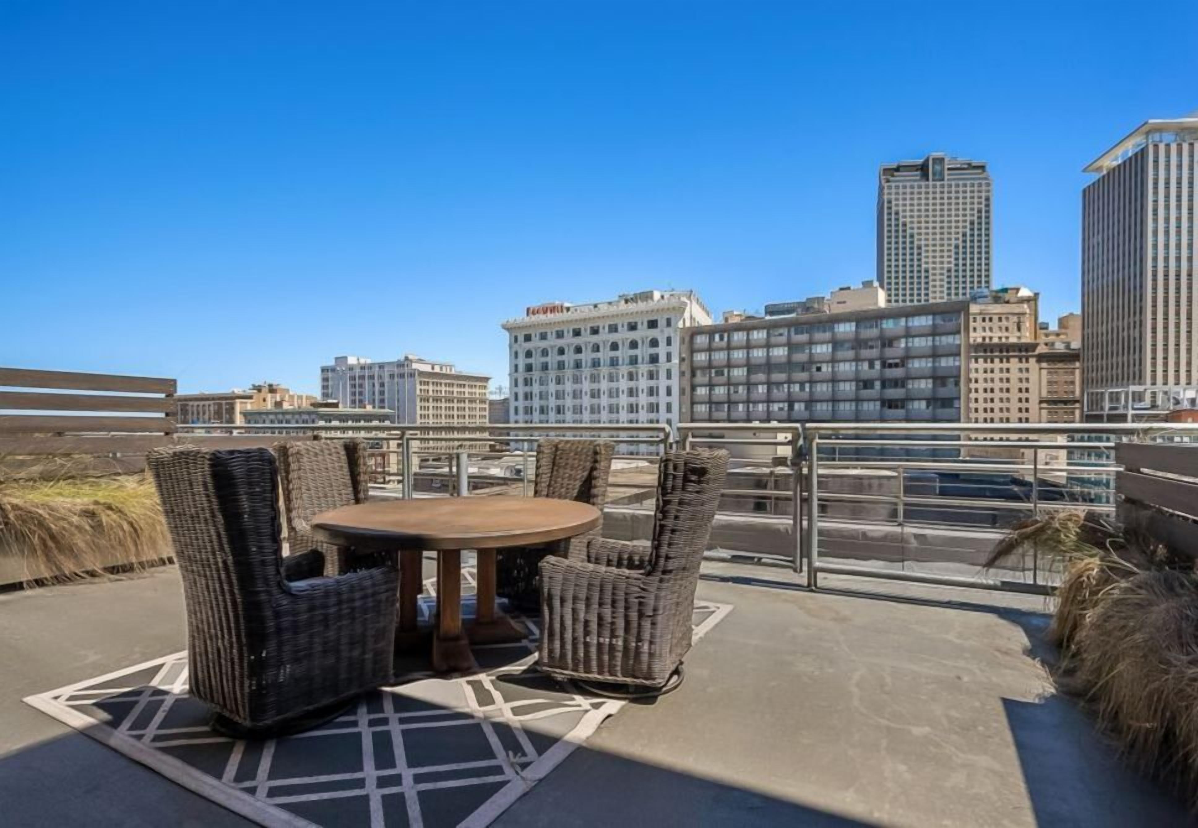 A rooftop terrace with wicker furniture and a city view.
