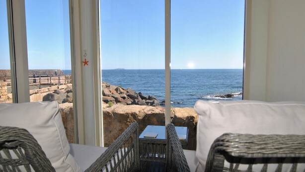 A balcony with wicker furniture, a view of the sea, and a rocky shoreline. - Aqua Vista- seafront cottage, Cellardyke (Anstruther)