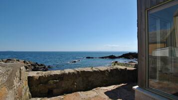 A coastal view from a stone building with a window overlooking the sea.