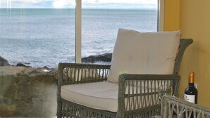 A wicker chair with a cushion by a window overlooking the sea. - Aqua Vista- seafront cottage, Cellardyke (Anstruther)
