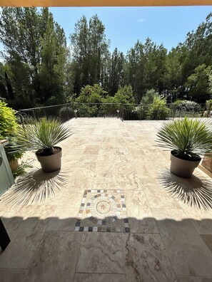 A paved patio with potted plants, a tiled mosaic centerpiece, and a metal fence. - Propriété de Campagne, Située Entre le Circuit Paul Ricard et Bandol (Le Beausset)
