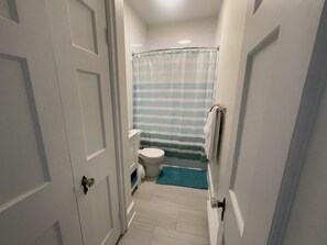 Une petite salle de bain comprenant des toilettes, un lavabo et un rideau de douche.