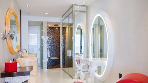 Un baño moderno con un espejo grande, un lavamanos y una cabina de ducha de vidrio.