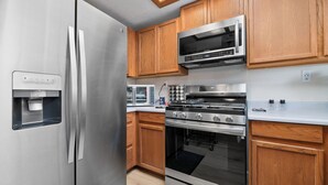 A modern kitchen with stainless steel appliances, wooden cabinets, and a built-in oven. - Casa De Campo (Big Bear City)
