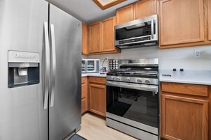 Una cocina moderna con electrodomésticos de acero inoxidable, armarios de madera y horno empotrado.