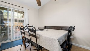 A dining area with a table set for four, a ceiling fan, and a view through a glass door. - Casa De Campo (Big Bear City)