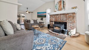 A living room with a fireplace, a sofa, a coffee table, and a rug. - Casa De Campo (Big Bear City)