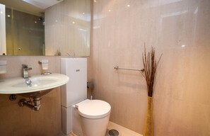 Moderni kylpyhuone, jossa on lasinen pesuallas, valkoinen wc-istuin ja peili pesualtaan yläpuolella.