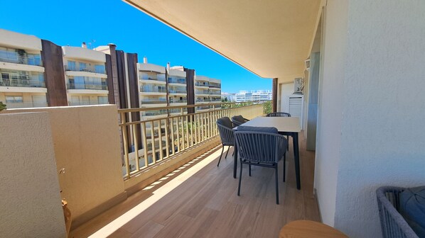 A balcony with a table and chairs, a view of other buildings, and a clear blue sky. - Ref: 298 Spacious seafront 3 bed/2 bath apartment with amazing views (Fuengirola)