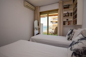 Hotellihuone, jossa on kaksi sänkyä, kirjahylly ja näkymä parvekkeelle.