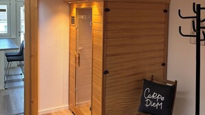 Une chambre avec un lit superposé, une armoire en bois et un petit coin salon agrémenté d’un panneau.