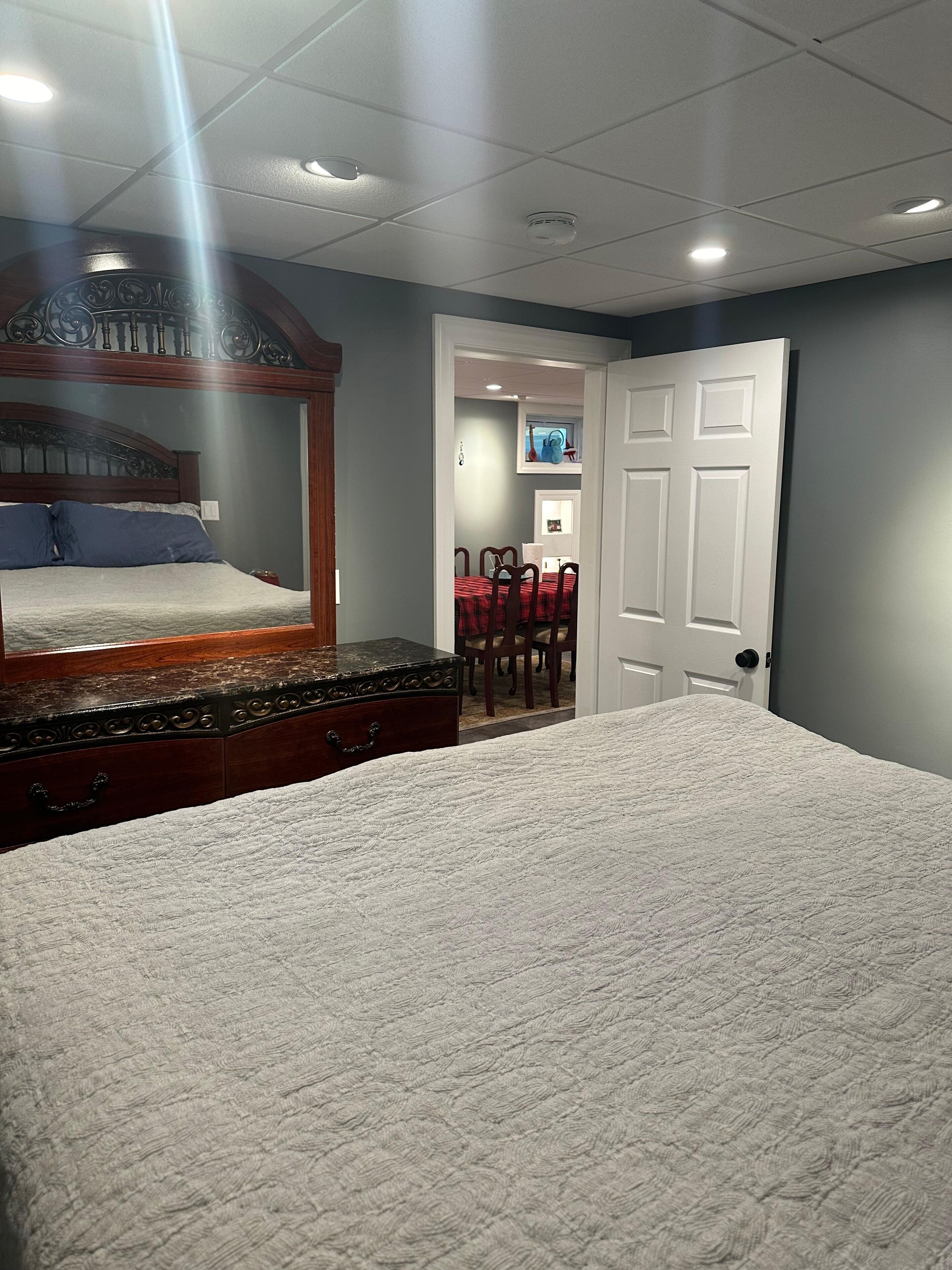 Ein Schlafzimmer mit einem großen Bett, einem Schminktisch, einem Spiegel und einer Tür zum Essbereich.