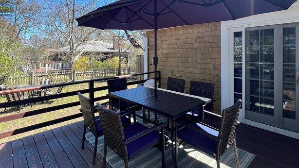 Eine Terrassengruppe mit Tisch und Stühlen, einem großen Sonnenschirm und einer Ziegelwand.