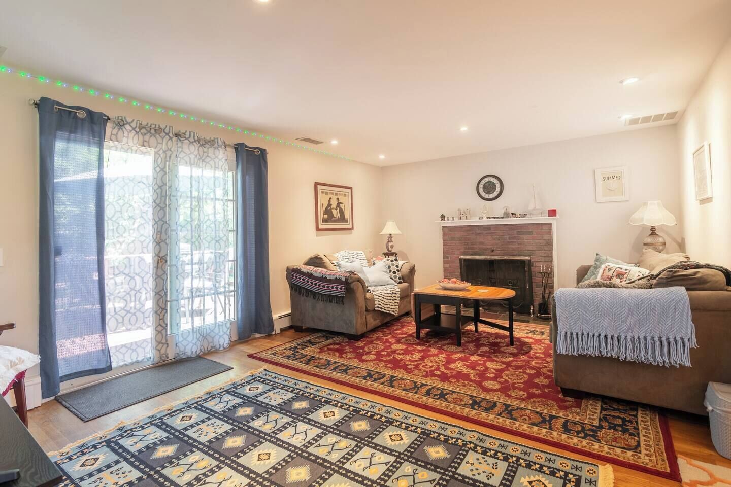 Una sala de estar con chimenea, dos sofás, una mesa de centro y alfombras estampadas.