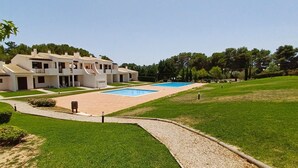 Un hotel moderno con piscina, un patio cubierto y un césped bien cuidado.