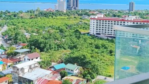 A high-rise building with a view of a coastal cityscape, including residential and commercial buildings, and a body of water. - The Mactan Newtown (Lapu-Lapu)