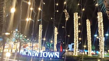 Illuminated vertical light strings and a neon sign reading "NEW TOWN" in a nighttime outdoor setting.
