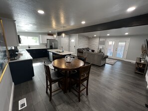 A spacious kitchen with a dining area, a living room, and a large sliding glass door leading to a balcony. - Cozy home centrally located  (West Valley City)
