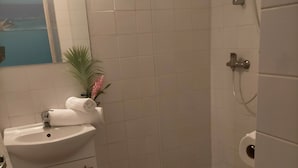 A bathroom with a white sink, a red bath mat, a shower, and a toilet. - Topaze Orientale Équipé Pour 2 Personnes Discret Sans Vis-à-vis! Vue sur Jardin! (Sainte-Rose)