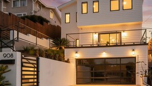 A modern two-story house with a garage, a gated entrance, and a number '908' sign.