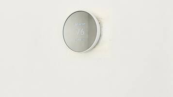 A thermostat with the brand 'Comfort' and model 'Indigo 75' on a white wall.